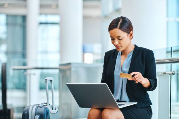 Woman with travel bag, booking flight with credit card and laptop. With capital one credit card travel plans